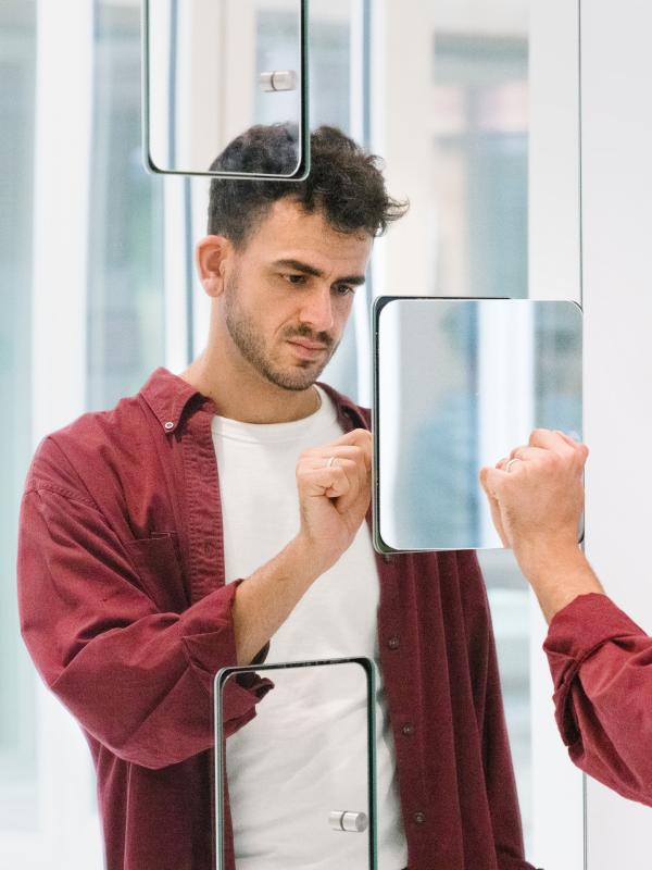 Mann interagiert mit seinem Spiegelbild vor einer Installation