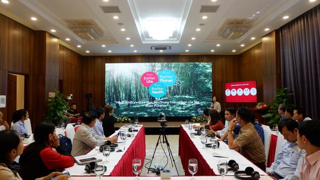 Group of people sitting at tables looking at a screen
