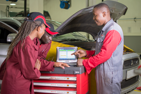 Eine Gruppe von Menschen, die neben einem Computer stehen.