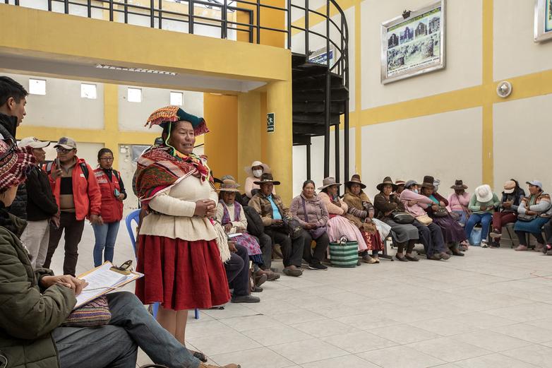 Kunsthandwerker*innen sitzen und stehen bei einem Treffen in einem Saal zusammen.