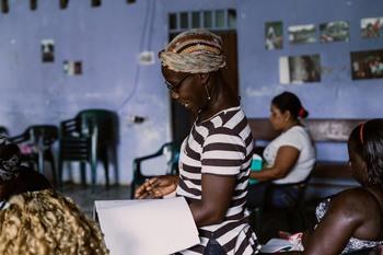 Eine Frau steht in einem Raum mit anderen Frauen und trägt etwas vor.