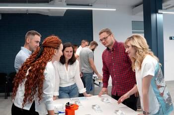 Personen stehen um einen Tisch und tauschen sich aus.