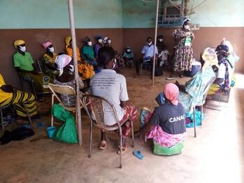 Frauen sitzen in einem Kreis und hören einer Lehrbeauftragten zu, die ein Notizbuch hält. © CiCDoc