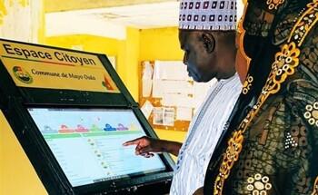 Ein älterer Mann tippt mit dem Finger auf dem Monitor eines großen Warenverkaufsautomaten.