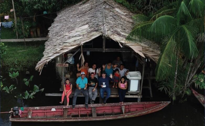 Eine Menschengruppe sitzt in einem Haus am Ufer des Amazonas und leistet Unterstützung bei der Landregistrierung.