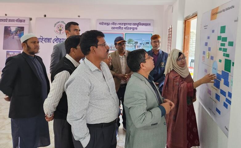 Eine Gruppe von Personen steht um ein Whiteboard und diskutiert gemeinsam Ideen und Informationen.