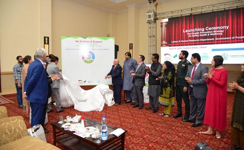 Eine Gruppe von Menschen steht in einem großen Konferenzraum und enthüllt gemeinsam ein großes Plakat.