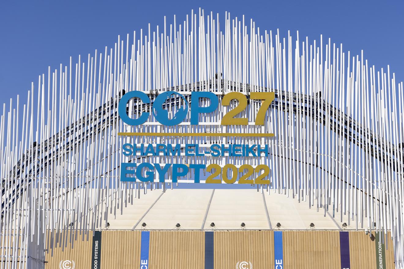 Eingangstor zur Klimakonferenz in Sharm El-Sheikh. Das Logo der Konferenz steht prominent in der Mitte des Bilds