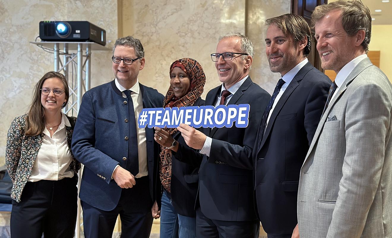 Sechs Personen posieren gemeinsam für ein Gruppenfoto, eine Person in der Mitte hält ein Schild mit der Aufschrift "#TEAMEUROPE".
