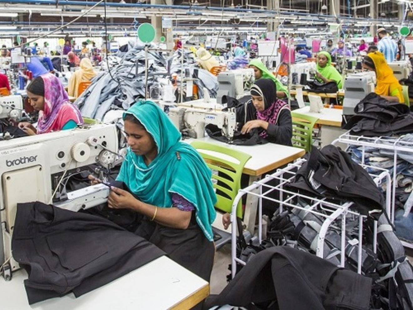 Mehrere Frauen nähen Kleidung in einer Fabrik.