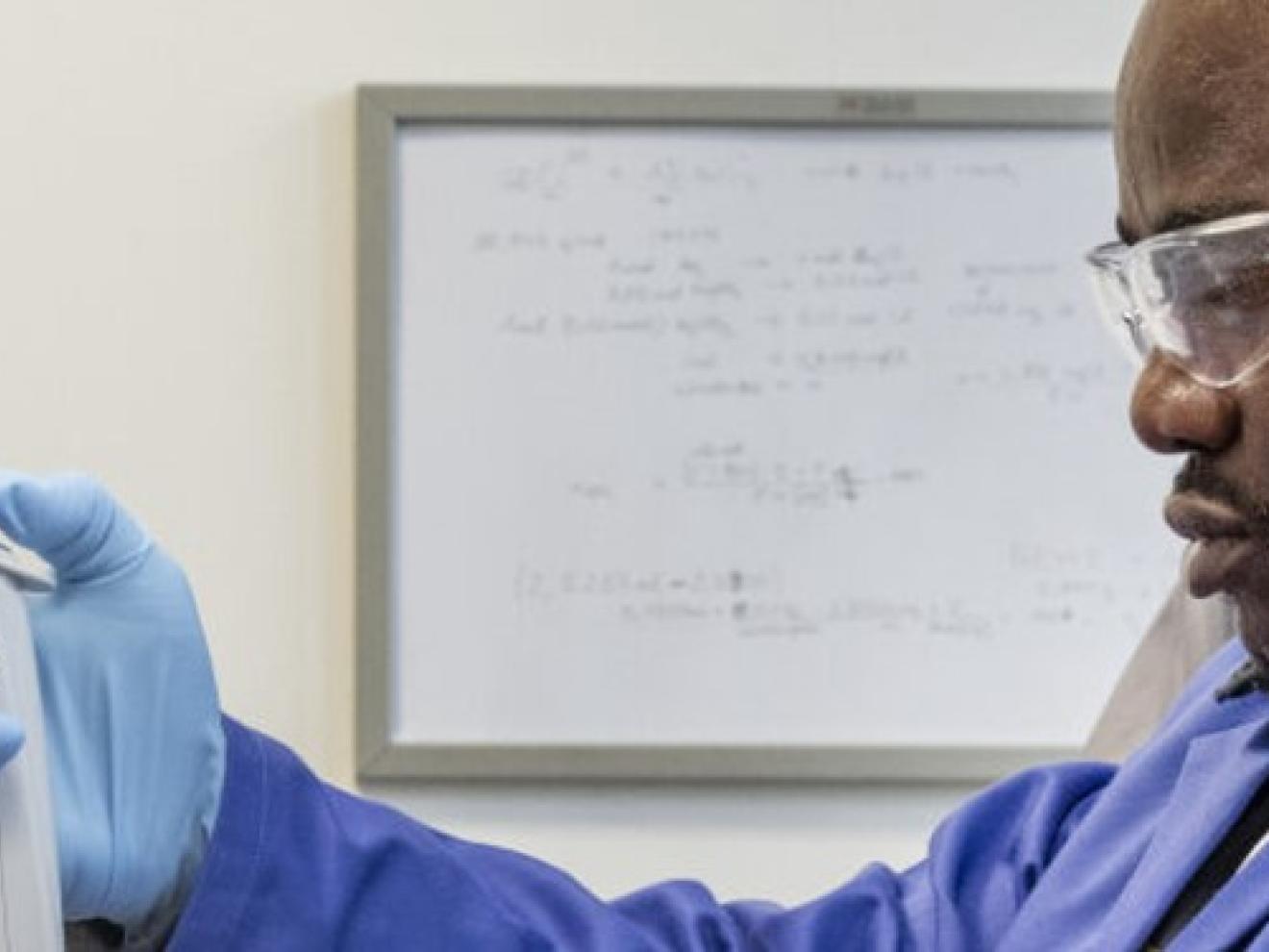 Ein Mann im Labor hält ein Messgerät in der Hand.