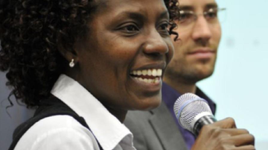 Eine Frau lächelt, während sie ein Mikrofon hält.