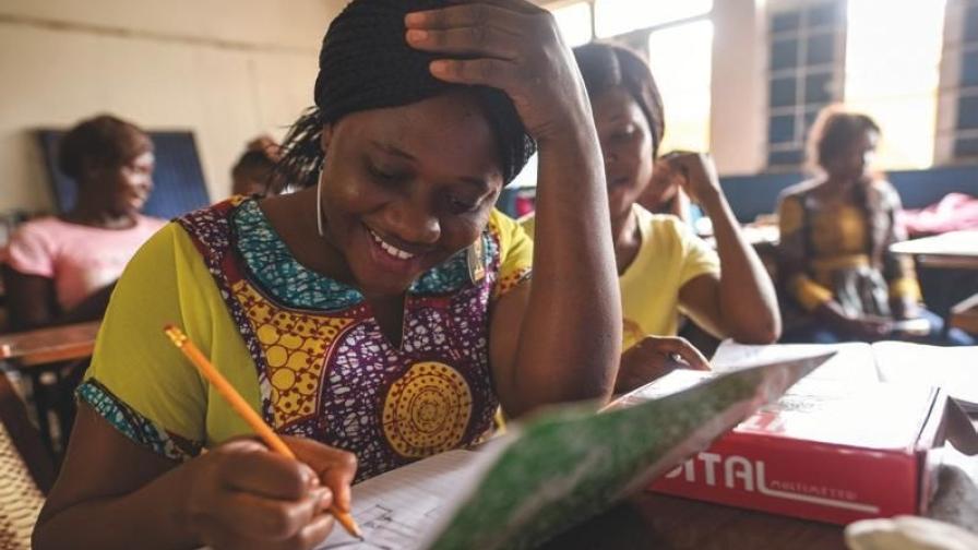 Frauen sitzen in einer Unterrichtssituation an Schulbänken.